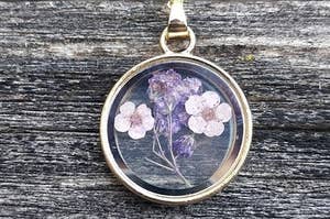 a dried lavender encased in glass on a gold chain