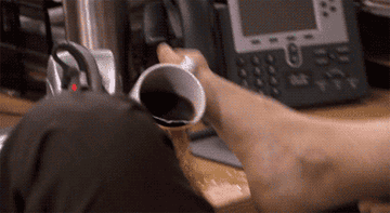 GIF of Dwight from The Office trying to drink coffee with his feet