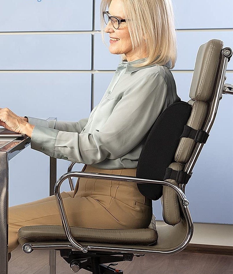 A person sitting in an office chair while using the lumbar pillow