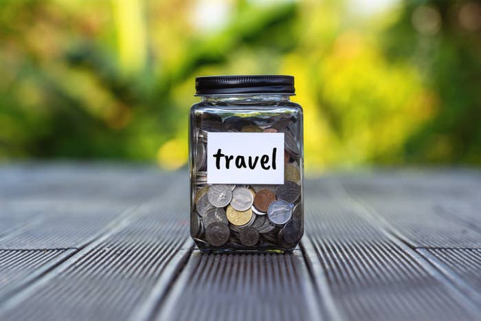 A jar labelled &#x27;travel&#x27; filled with coins.
