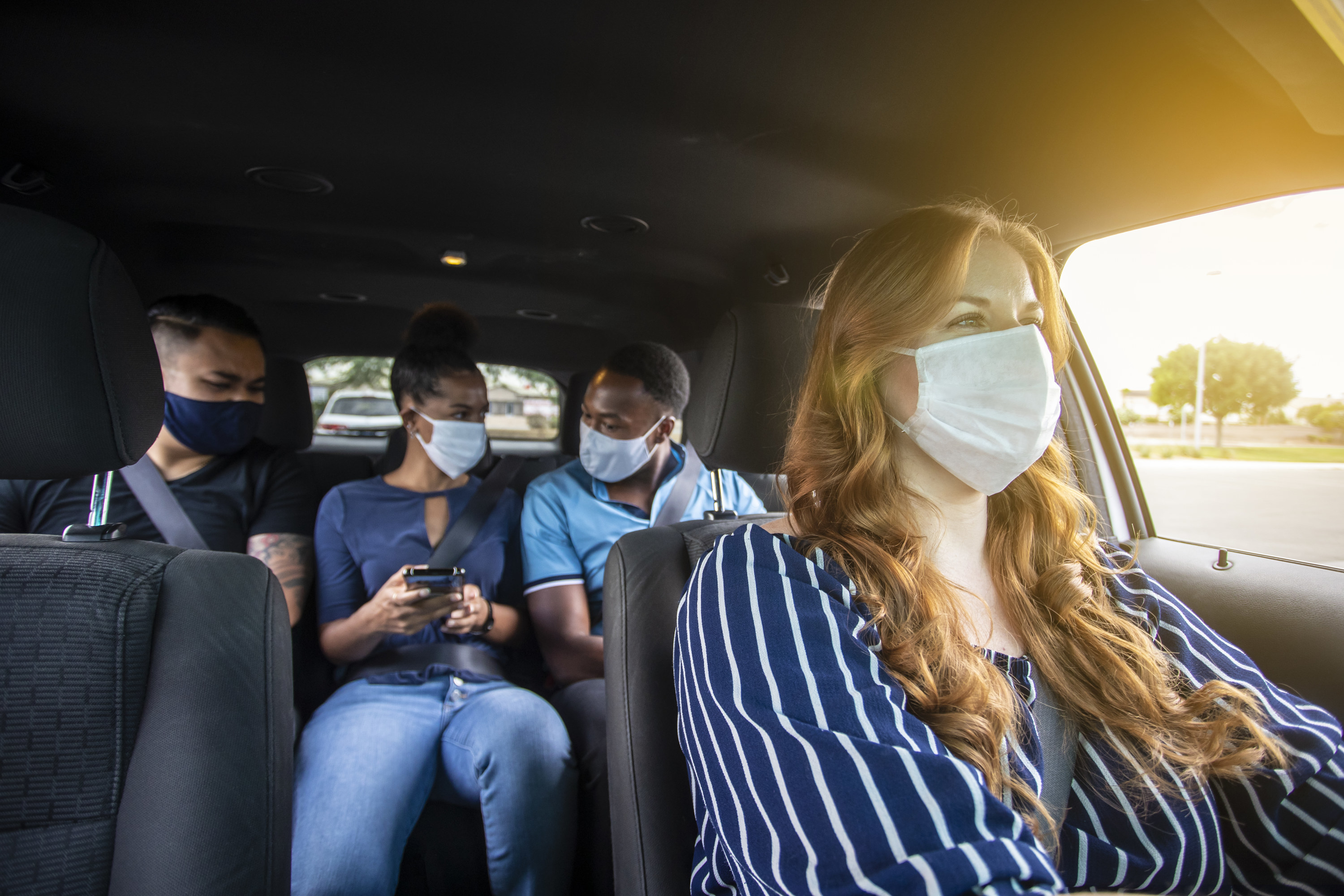 A group of people wearing masks and using a ride sharing service
