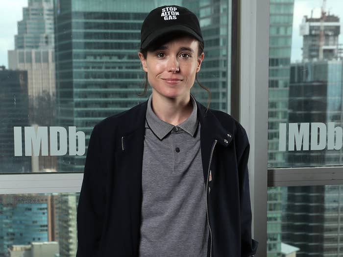 Elliot smiles while wearing a baseball cap, grey polo and black zip up hoodie