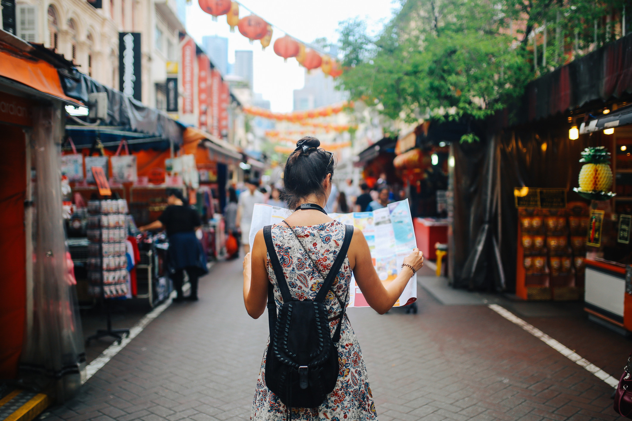 A young woman carrying a map while walking on the street.