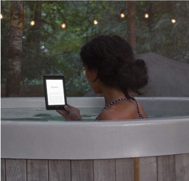 Foto se persona utilizando un Kindle para leer mientras toma un baño