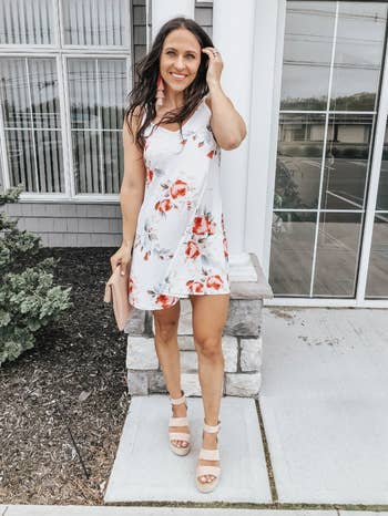 a reviewer wearing the tank dress in white with a red floral print