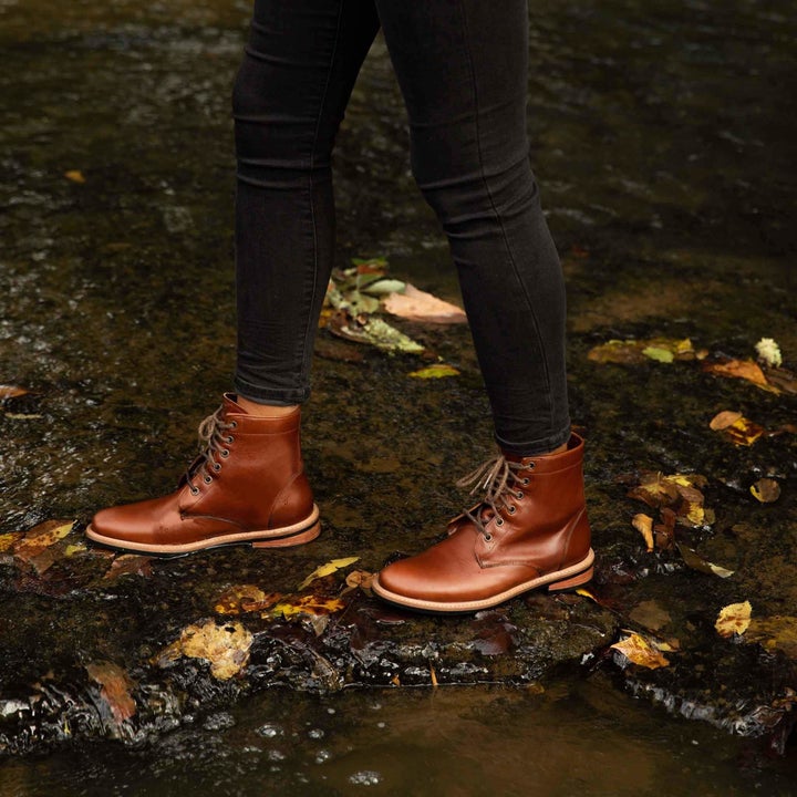 model wearing the boots in dark brown standing on wet, muddy ground