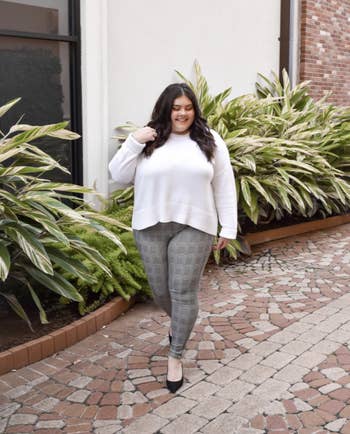 reviewer wearing gray plaid leggings with white sweater and flats