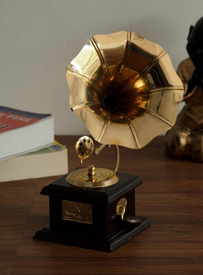 A brass gramophone showpiece with a wooden base and brass crank