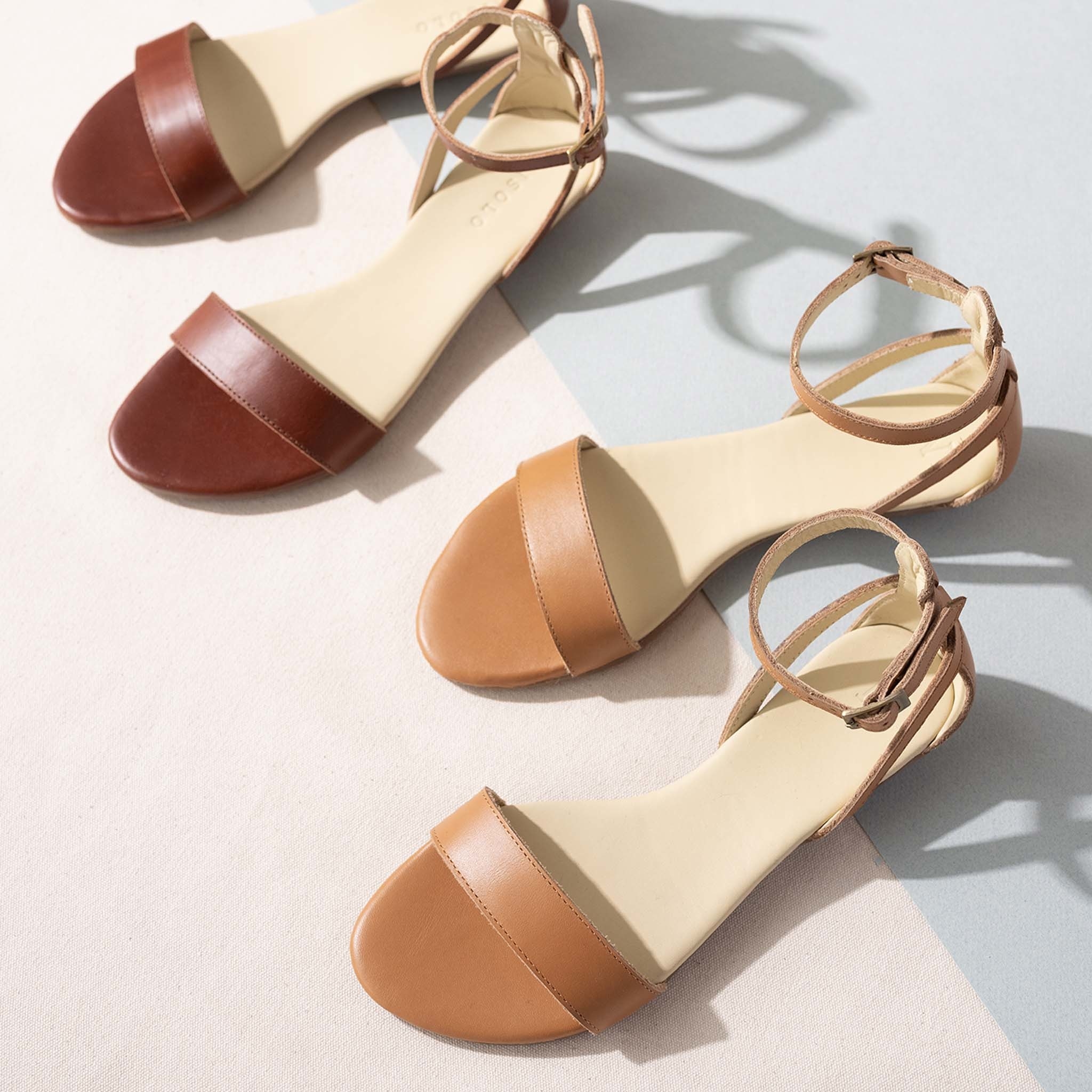 two pairs of the sandals. one in tan and one in dark red.