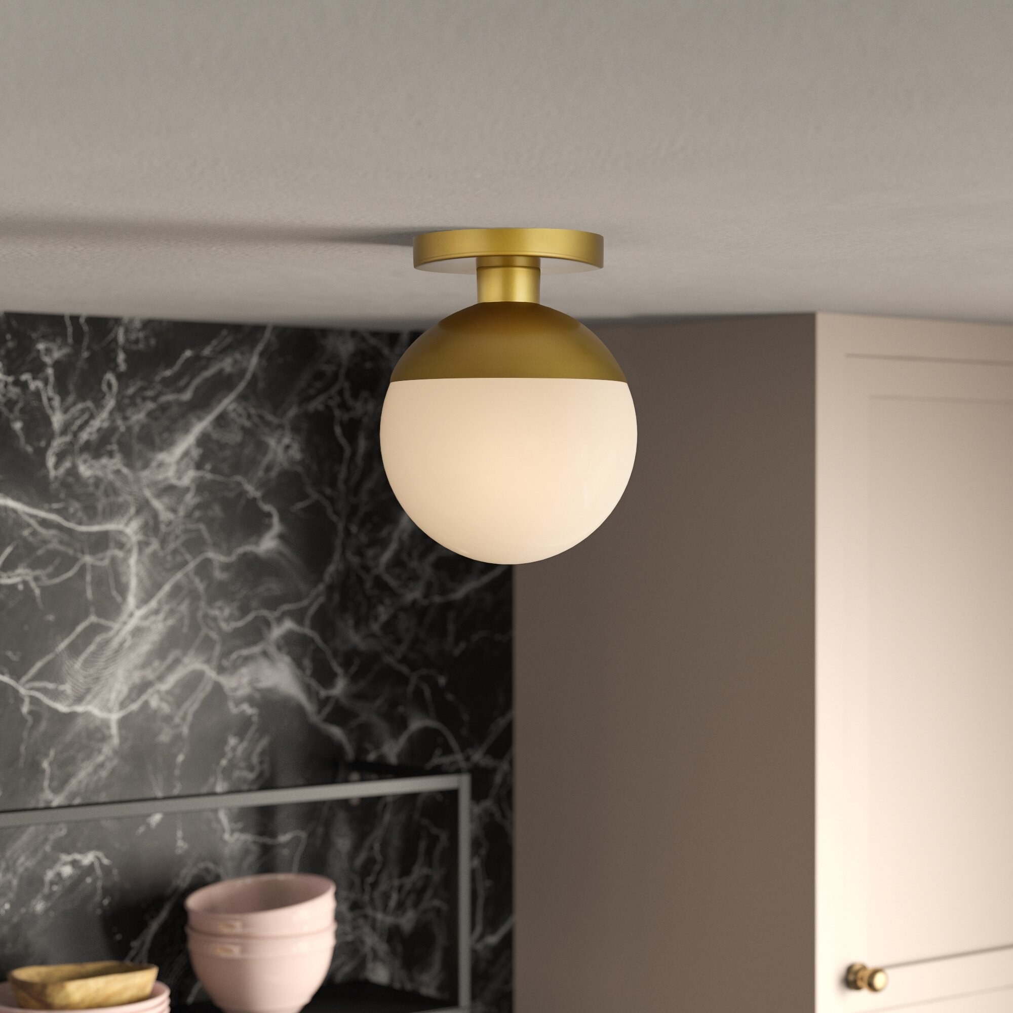 a globe ceiling light with a frosted bulb and gold base