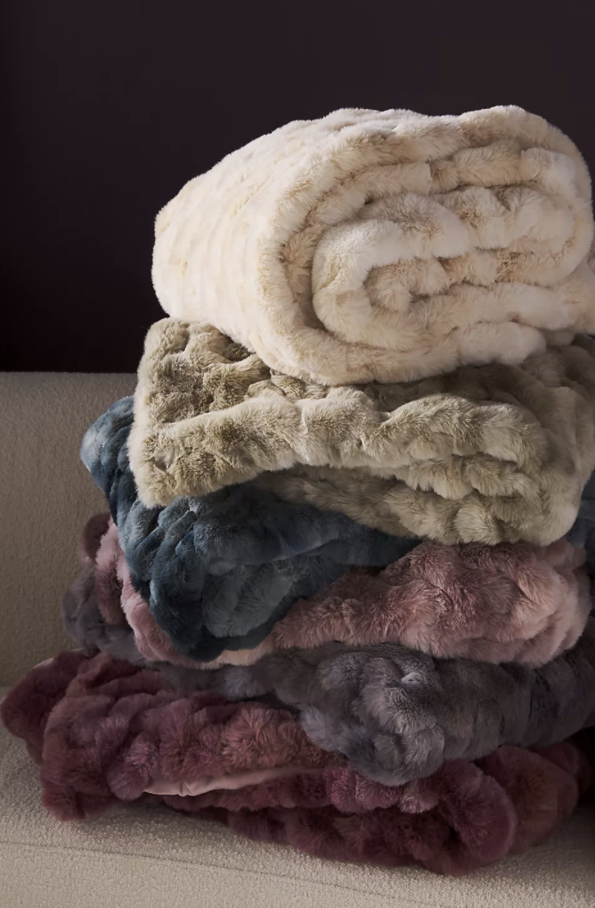 a stack of plush throw blankets in different colors