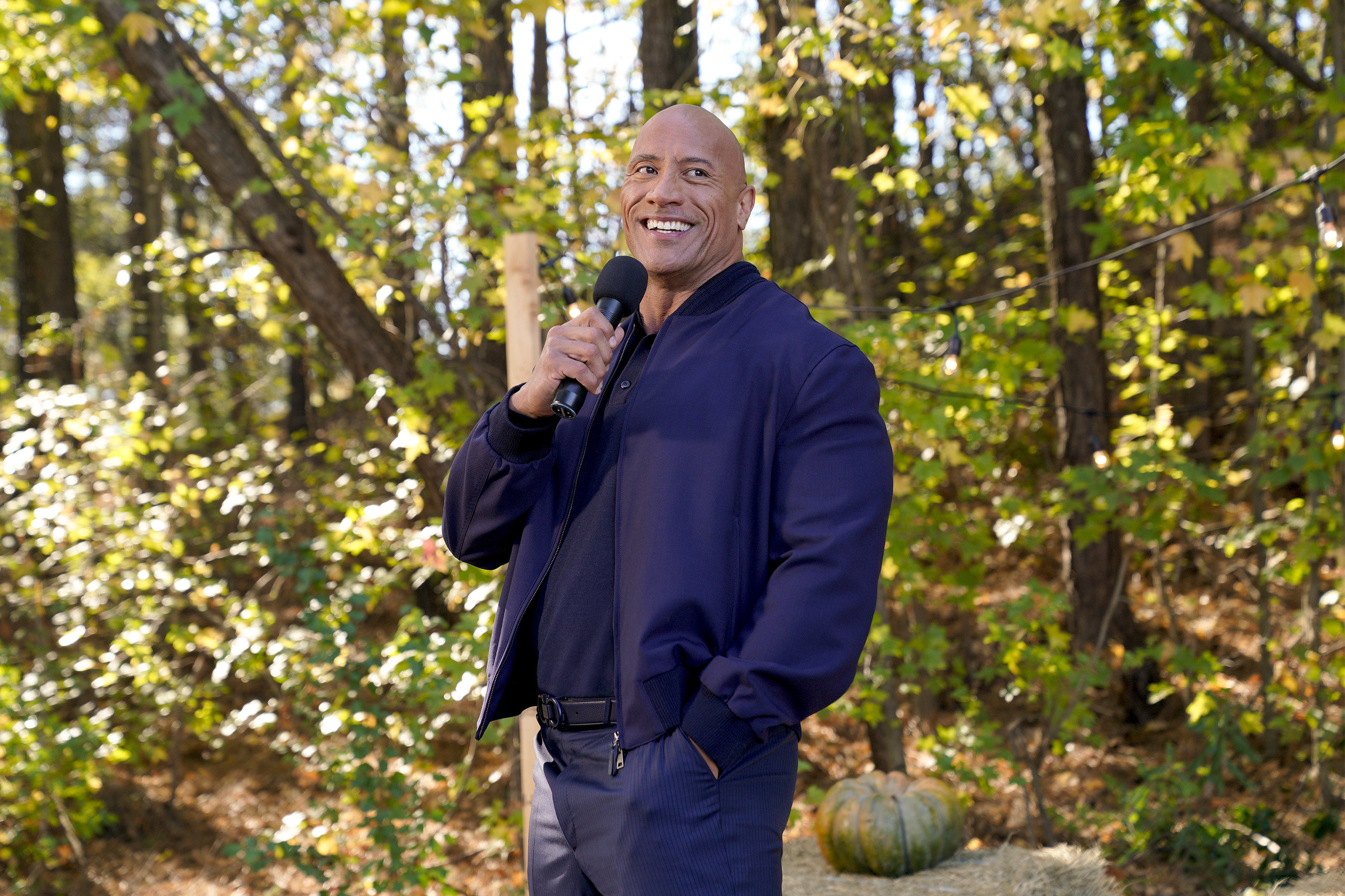 Dwayne Johnson smiling and standing in front of trees