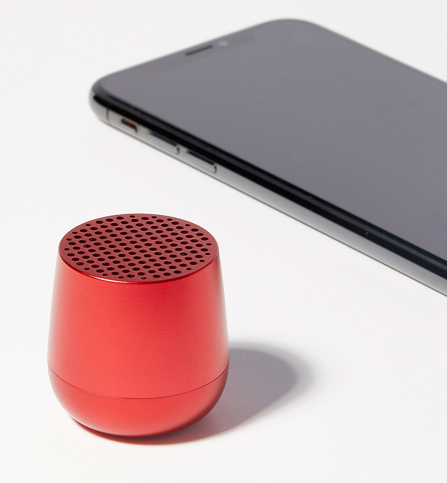 The mini bluetooth speaker next to a cell phone for scale