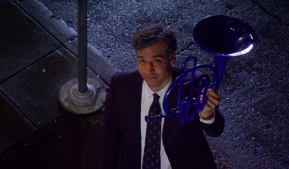 Ted holding up the blue French horn on the sidewalk