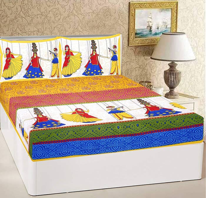 A colourful bed sheet with images of a man and woman dressed in traditional wear