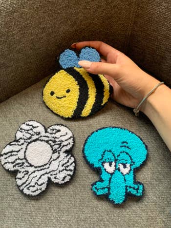 three plush coasters. clockwise they are a yellow bumblebee, the face of Squidward from the Spongebob show, and a white and black striped daisy.
