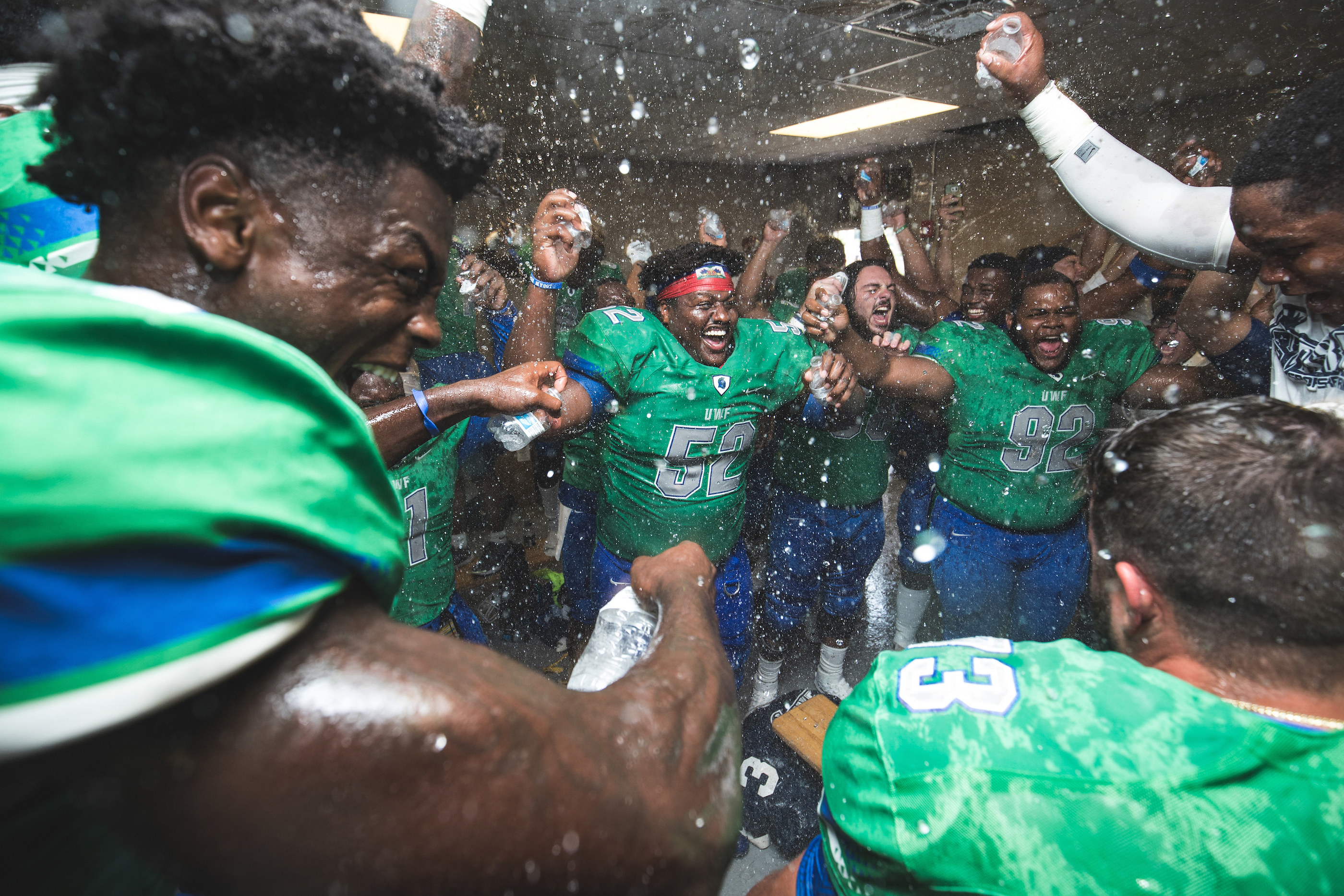 Football players celebrate a victory in their locker room after a game