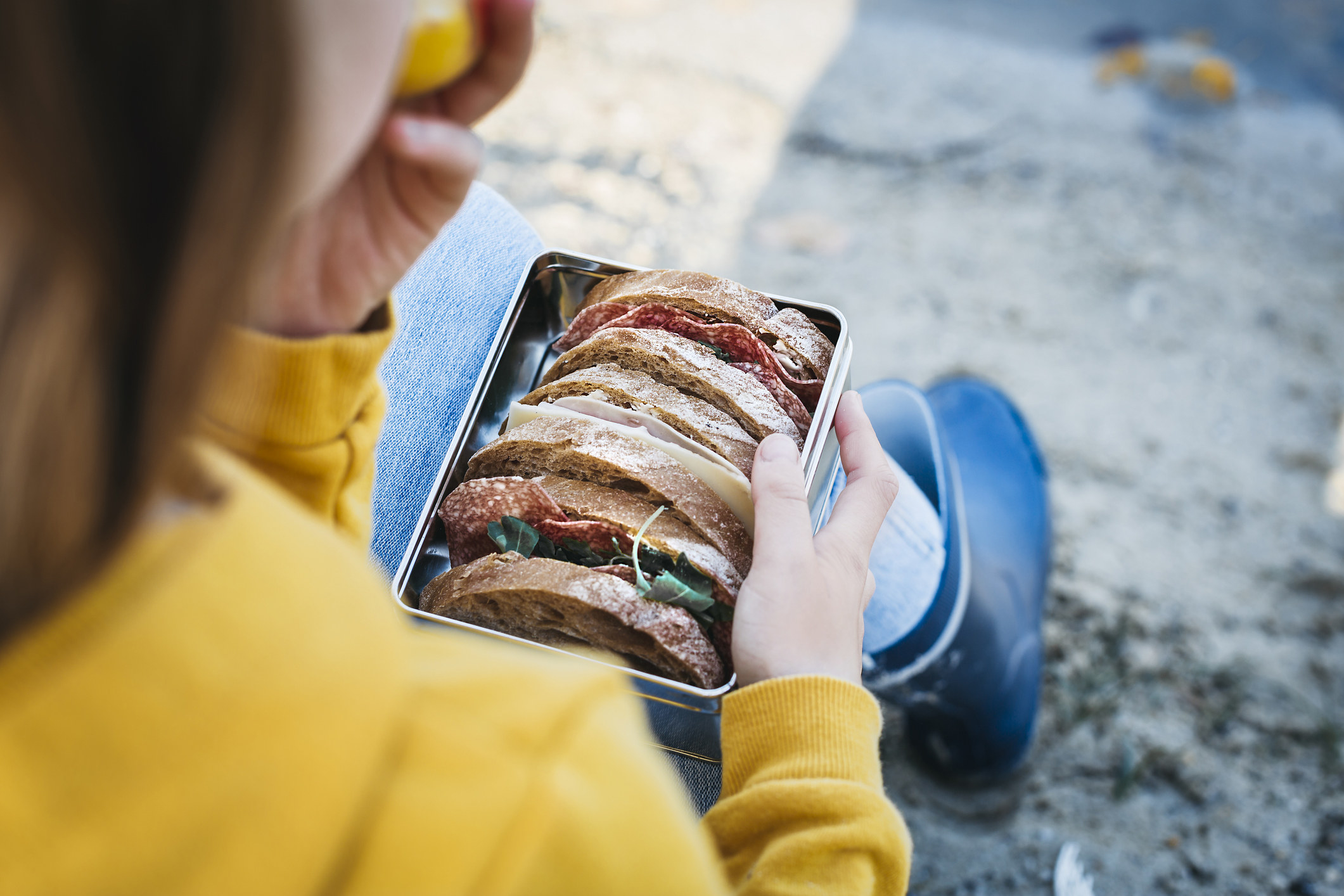 A woman eating a sandwich outside.