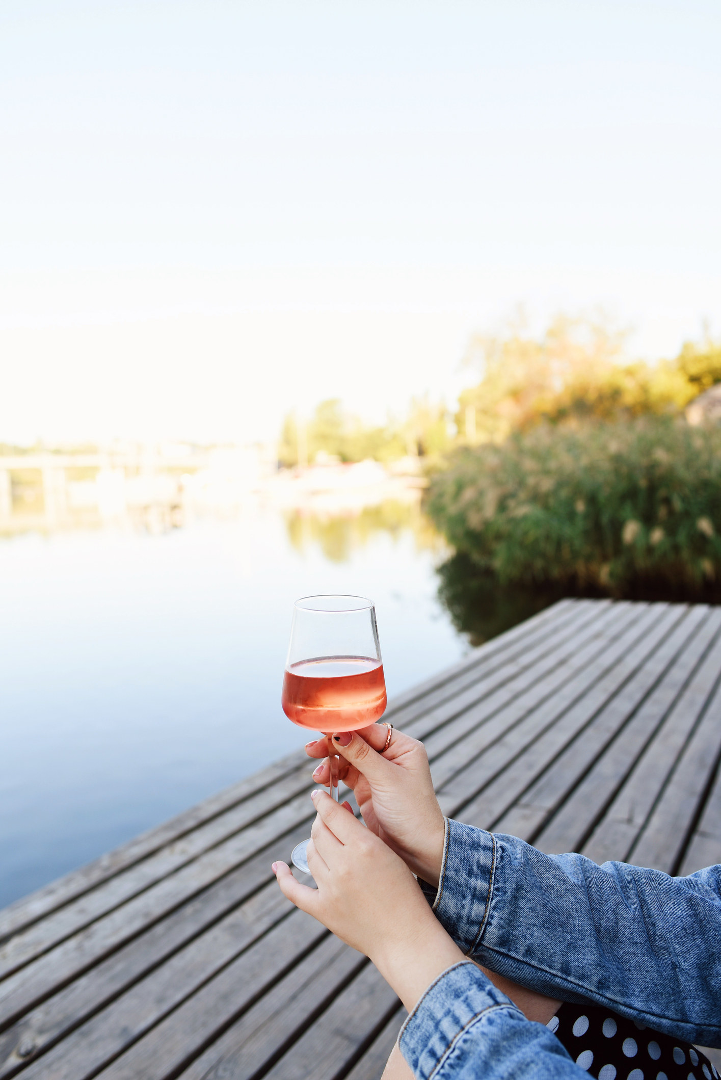 Someone drinking a glass of rosé on a dock.