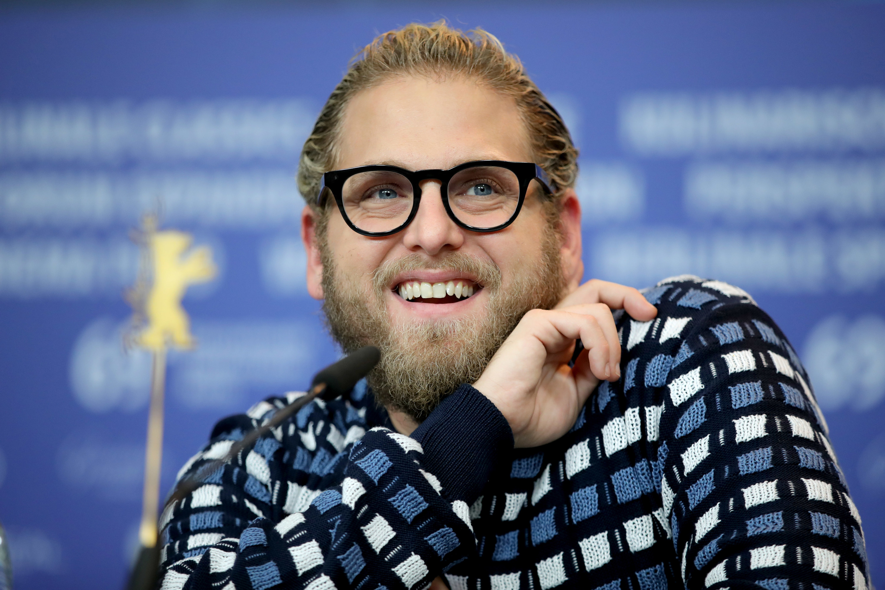 Jonah smiles while wearing a blue white and black checked sweater