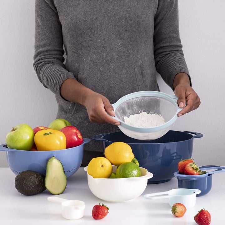 A person using the sieve with all the other items neatly arranged around them on a counter