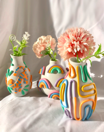 three polymer clay vases with a white background and 3D colorful prints on them. The first has a tiger in orange and blue, the middle has 3D rainbows, and the thrid has different lines looping in random colors