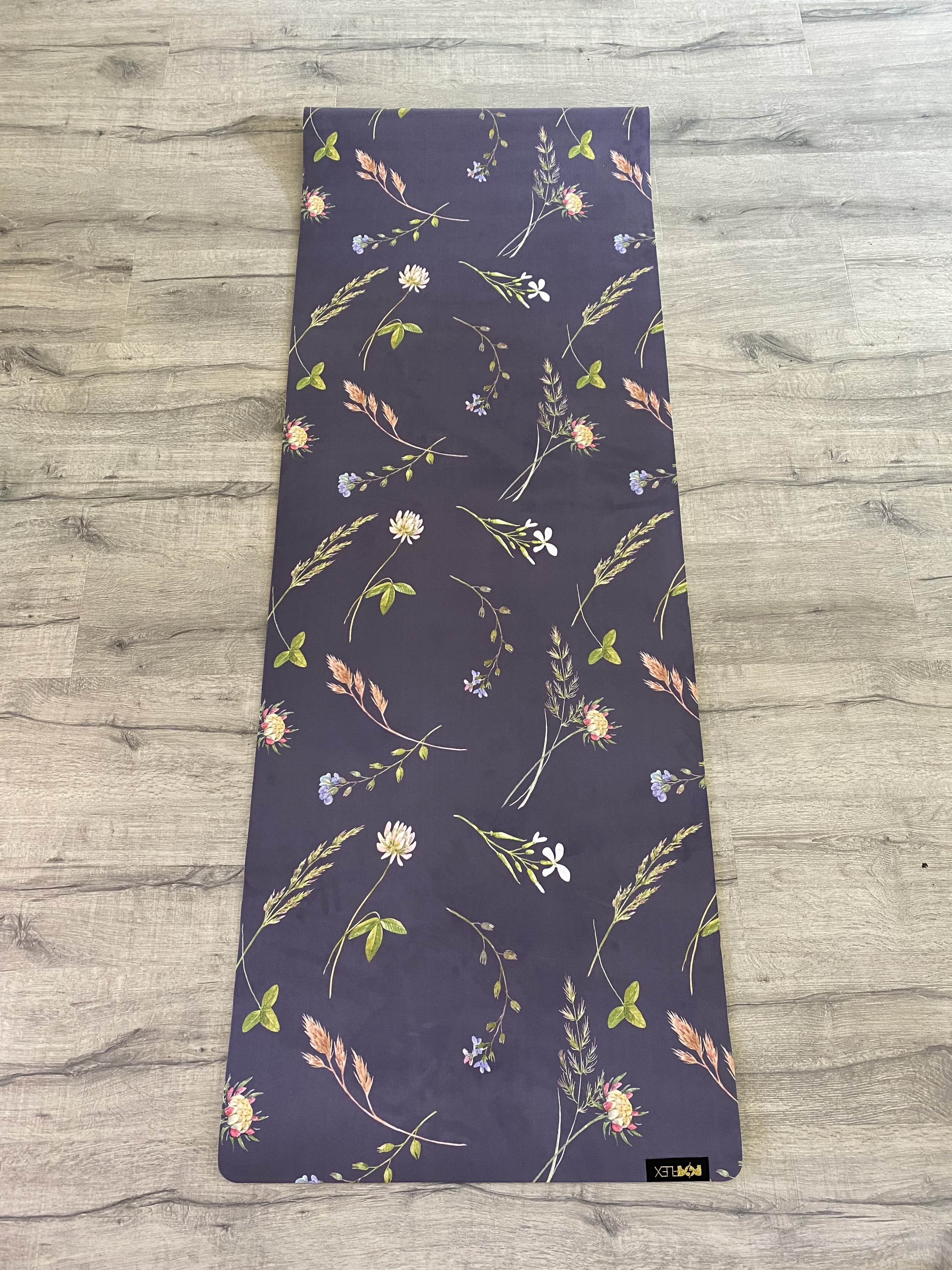 The yoga mat laid out on the floor, with a whimsical floral print