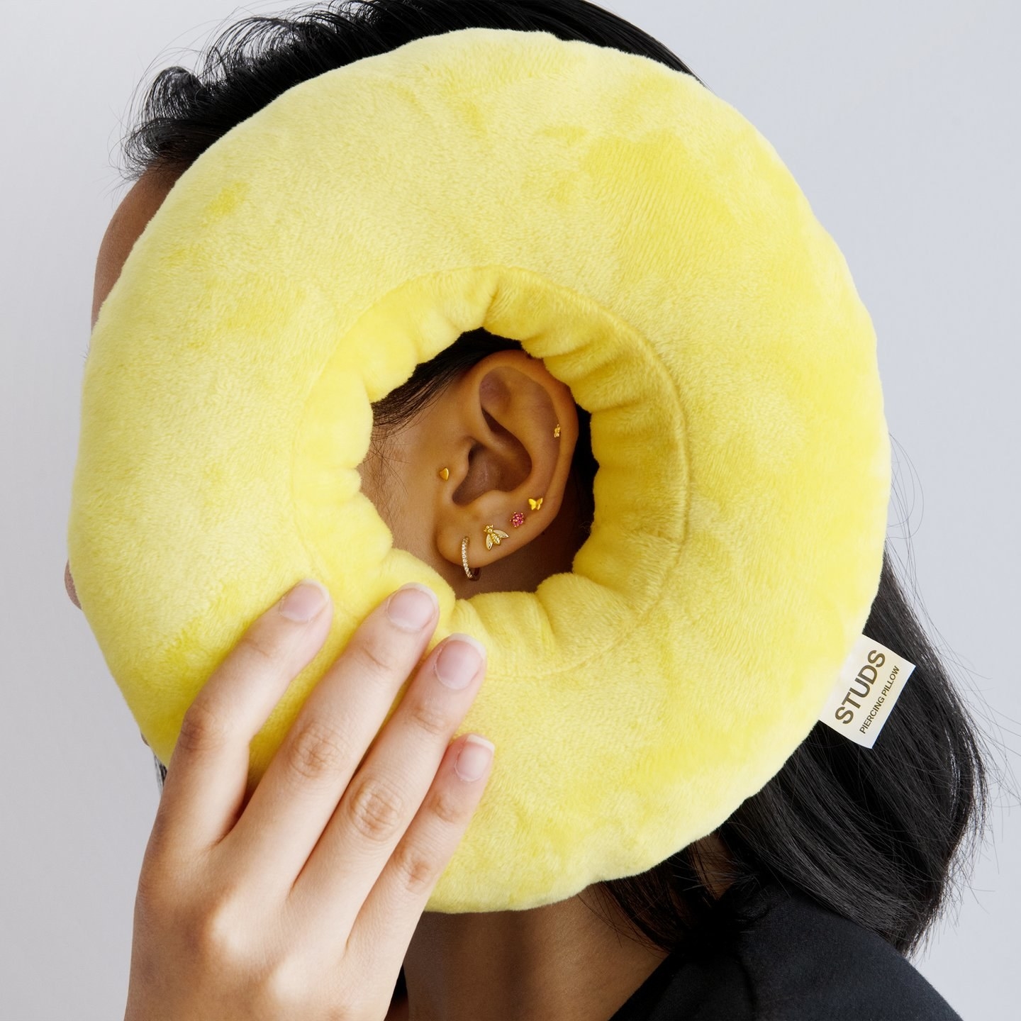model holding a yellow circular pillow with a hole in the middle for your ear to reset