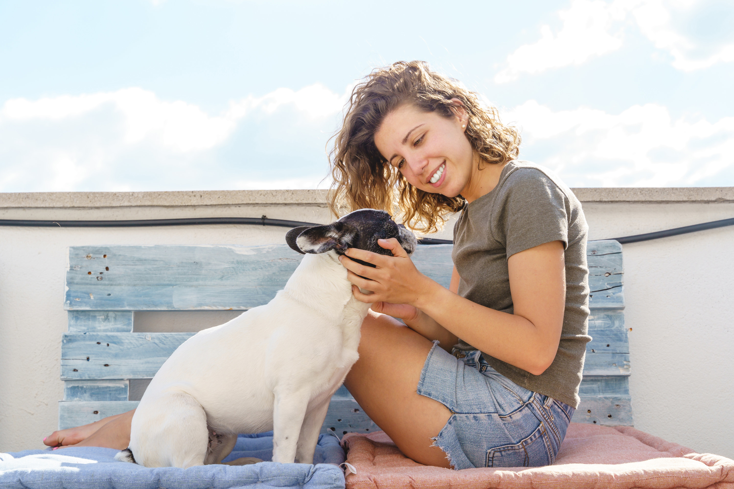 A young woman cups her dog&#x27;s face in her hands