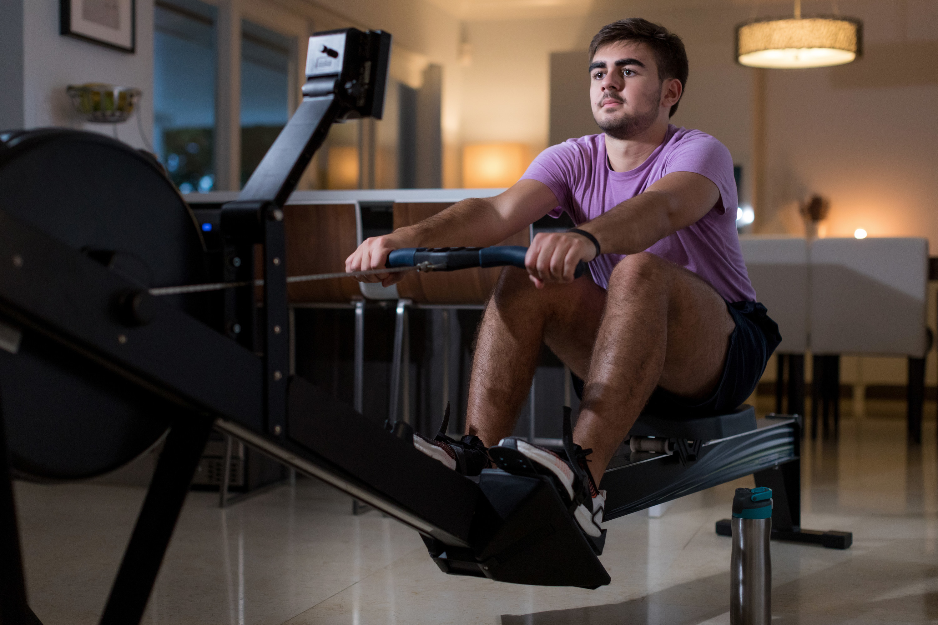 A man uses a rowing machine in his apartment