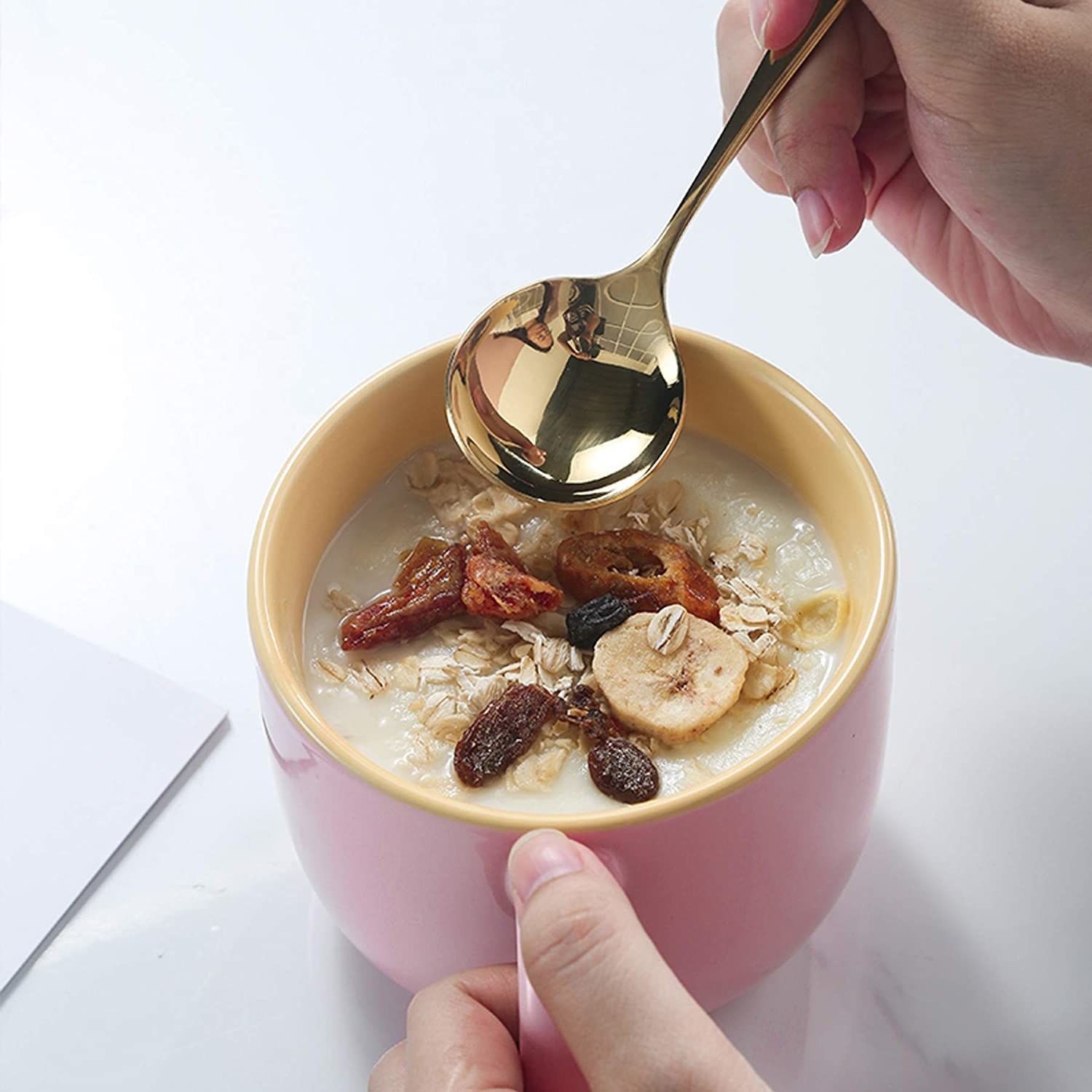 Someone dipping a spoon into the mug; it is filled with oatmeal