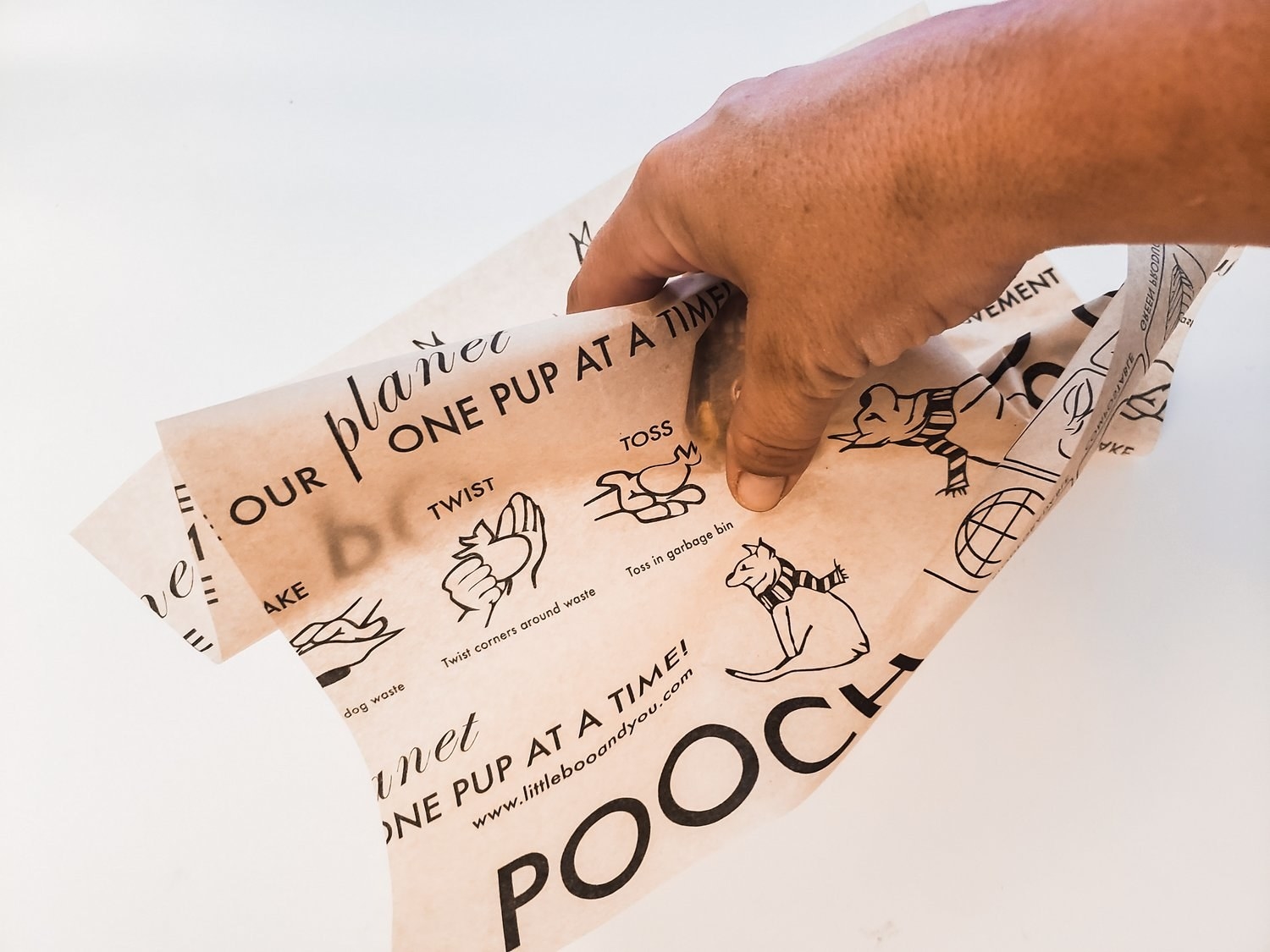 hand picks up poop with paper