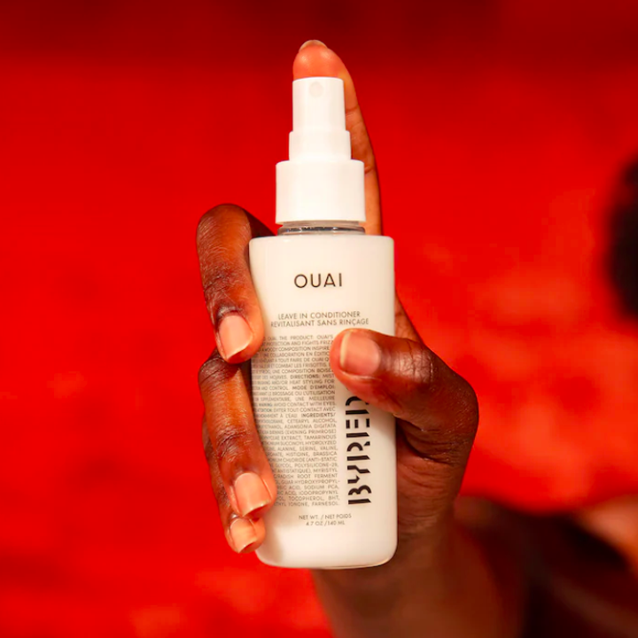 A person holding a bottle of the leave-in conditioner