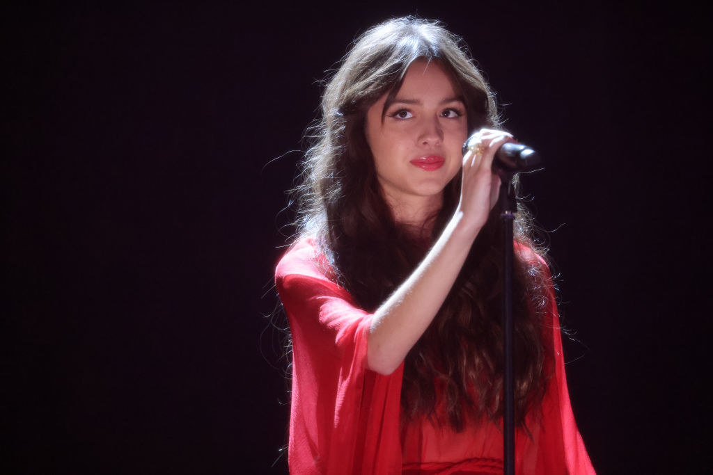 Olivia holding a microphone as she performs on stage