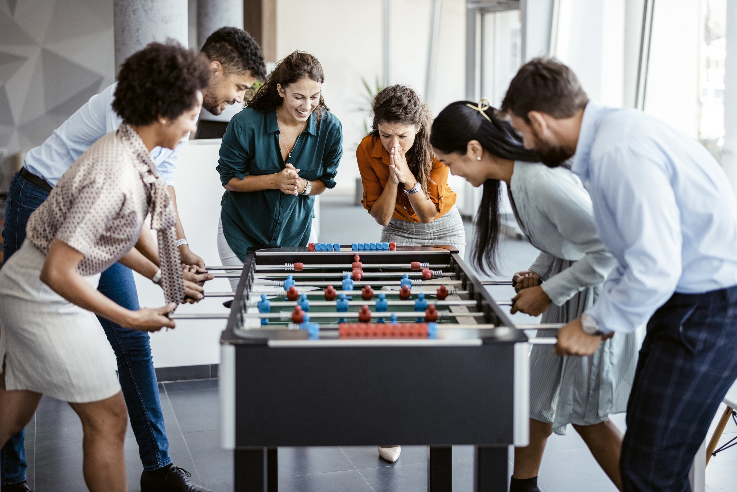Employees crowded around a foosball table