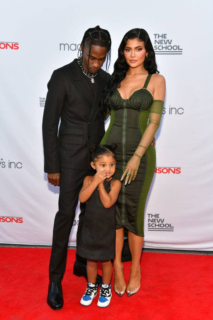 Kylie poses on a red carpet with Travis Scott and their daughter Stormi