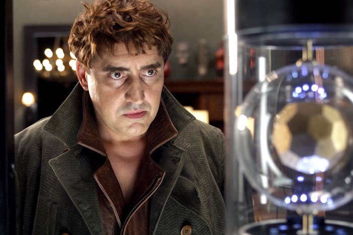 Alfred Molina stares at something in a glass case as Doc Ock in Spider-Man 2