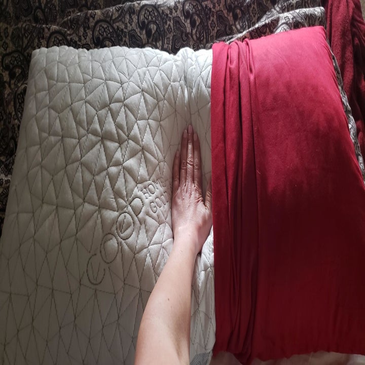 Reviewer pushing the pillow with their hand to show its plushness