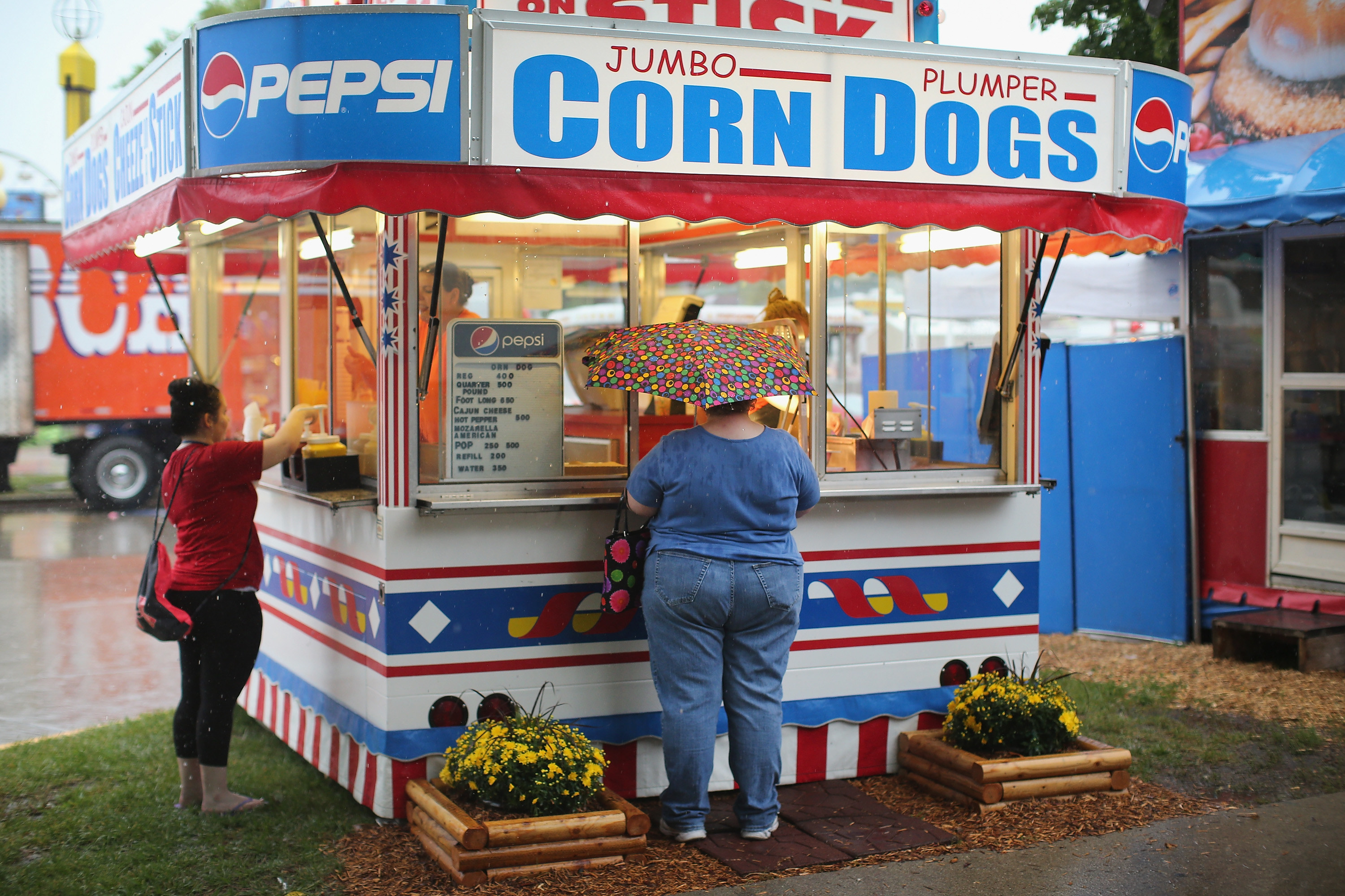 Fair attendees order food at a corndog stand on a rainy day at the Iowa State Fair