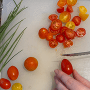 Gif of hands slicing cherry tomatoes into tiny pieces easily with the knife 