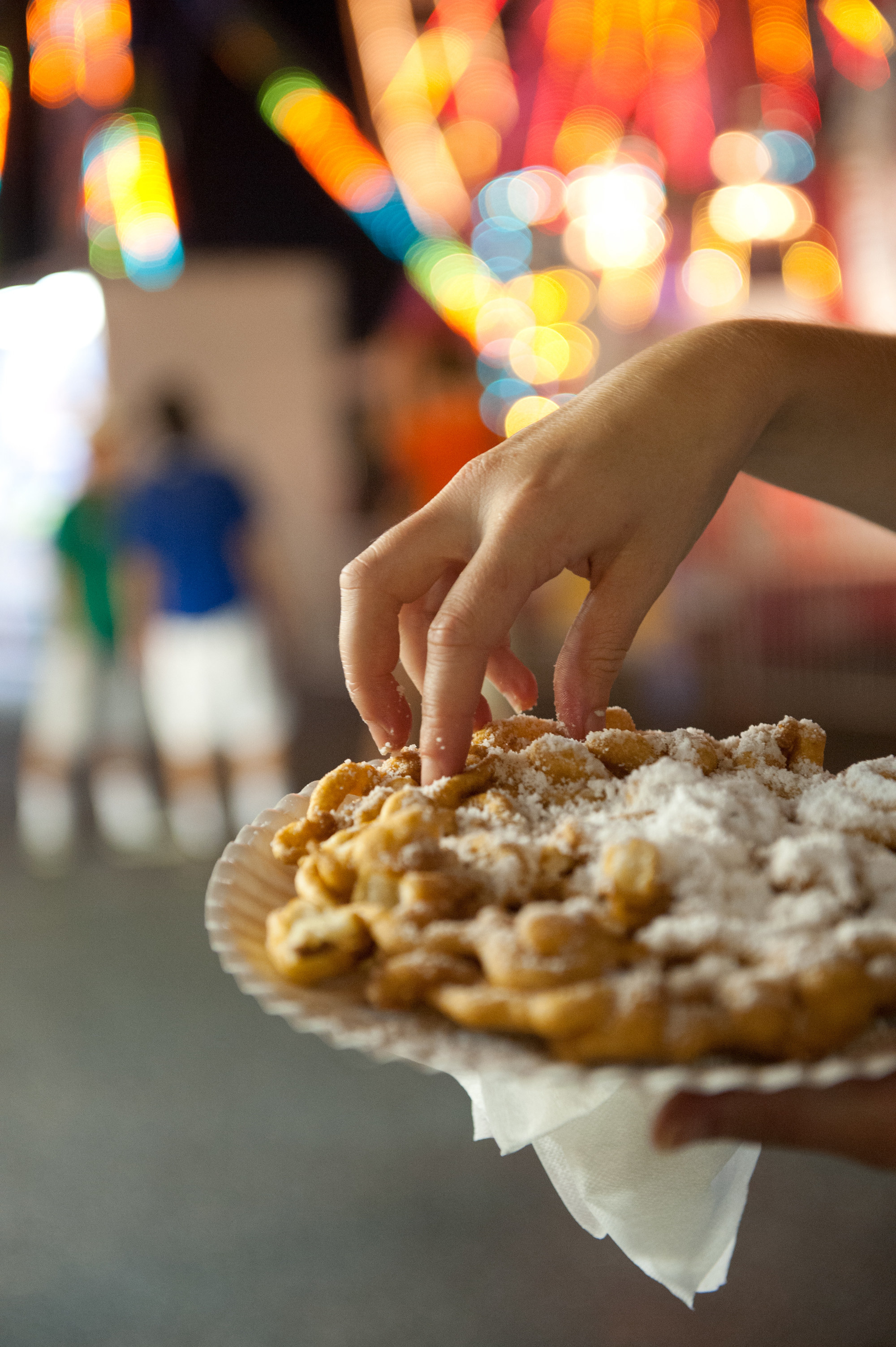 A person holds a sugar topped funnel cake in hand at the Maryland State Fair