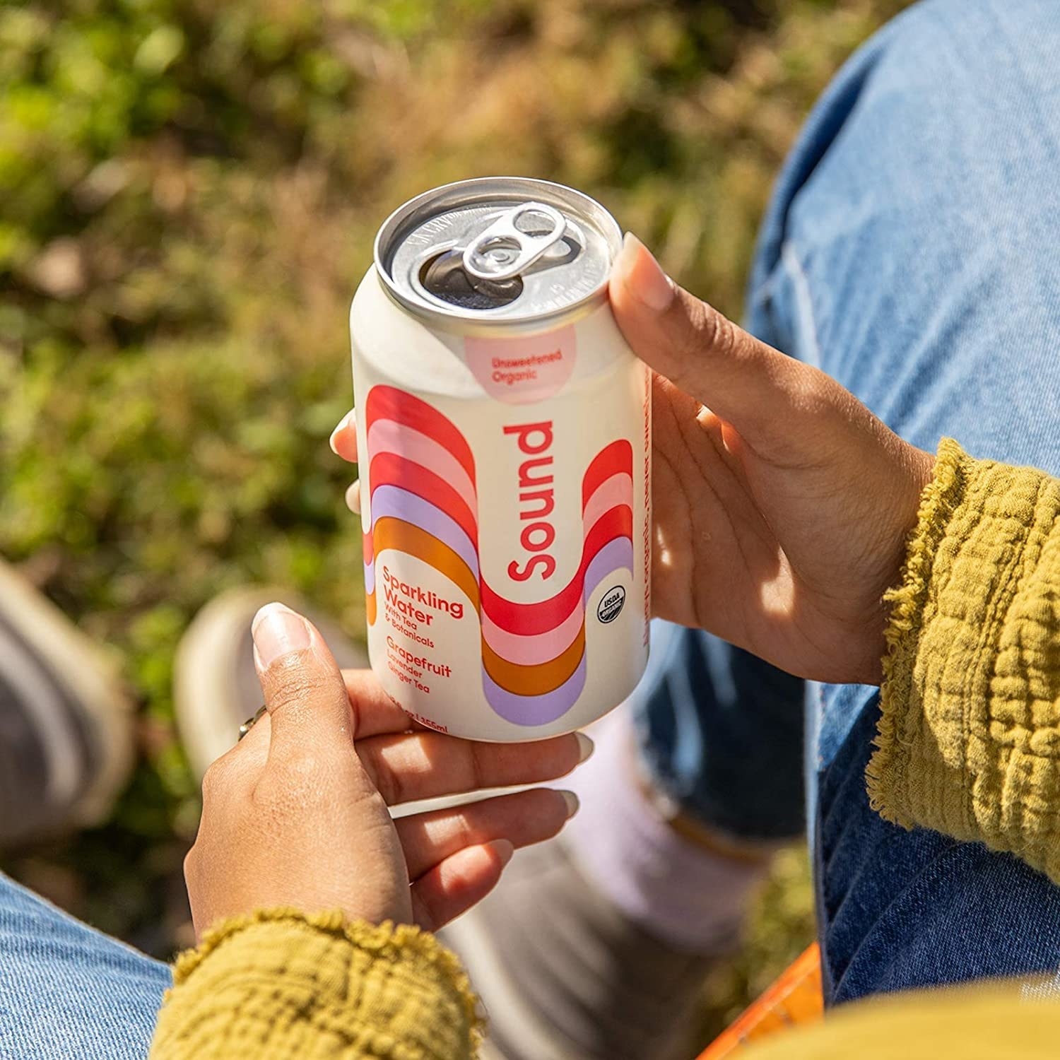 hand holding a can of sparkling water with colorful wave design on it
