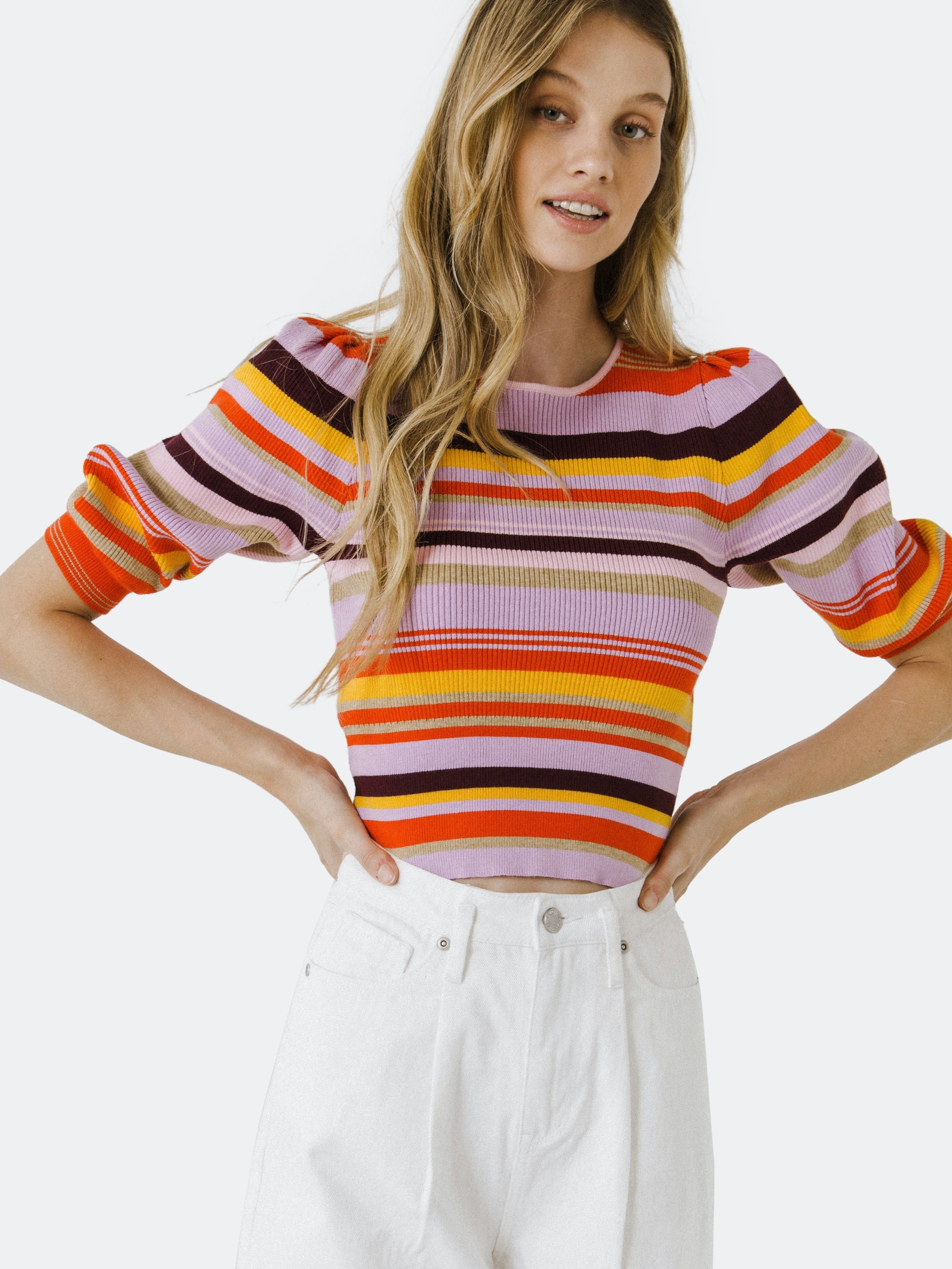 a model wearing the striped colorful sweater with white jeans