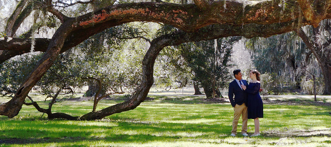 Nathan and Caroline posed underneath a tree in a park.