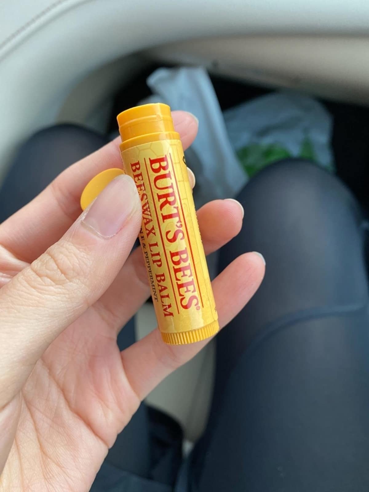 Reviewer holding tube of Burt&#x27;s Bees lip balm