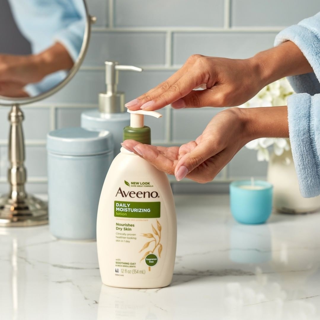 Model pumping Aveeno Daily Moisturizing Lotion into their hand