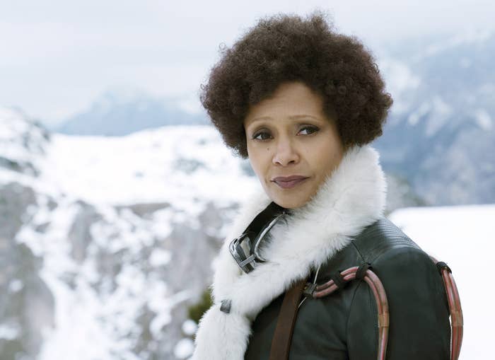 Thandiwe portrays Val, who stands in front of snowy mountains in a leather jacket with a white fur collar