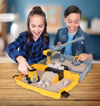 Two models playing with the the kinetic sand folding sandbox playset 