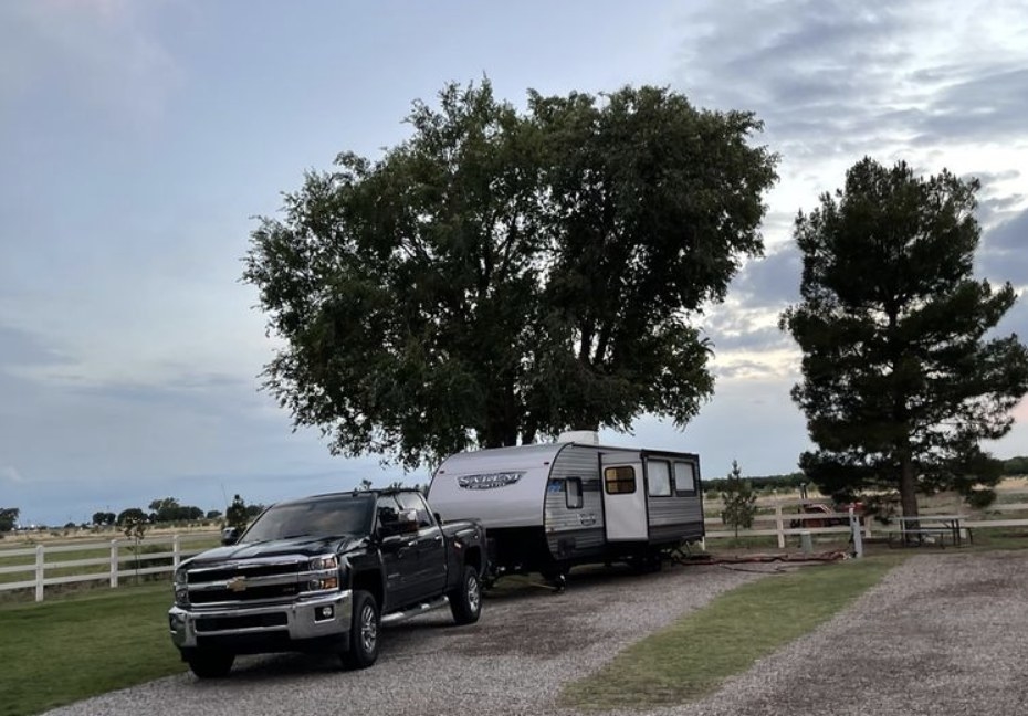 Truck and RV parked near a gate and under a tree