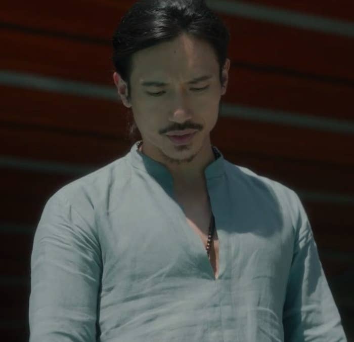 Yao stands outside during the daytime, looking down